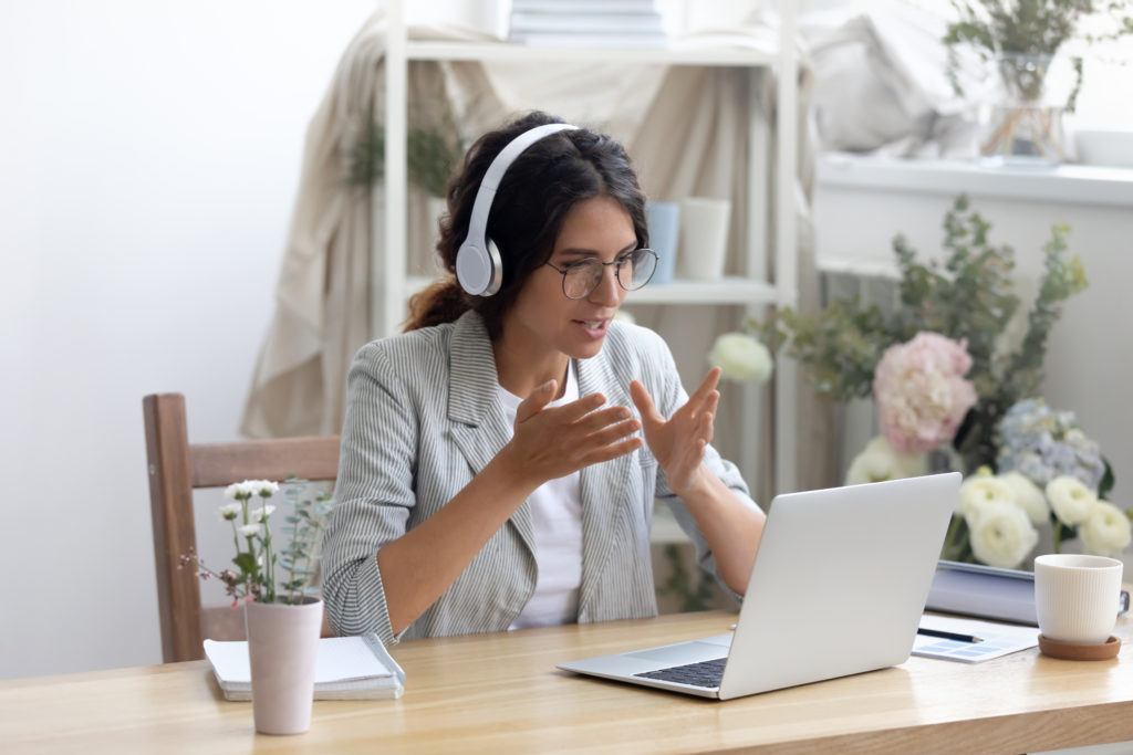 Woman wearing headphones on a video meeting at a laptop